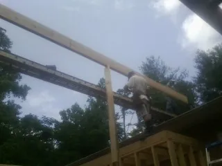 Carpenter setting a ridge beam over a new addition frame — Ice Dam Removal by Roofing Brothers in Ostrander