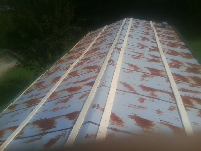 Rusted metal roof panels with new wood purlins before replacement — Storm Damage Roof Repair in Ostrander by Roofing Brothers