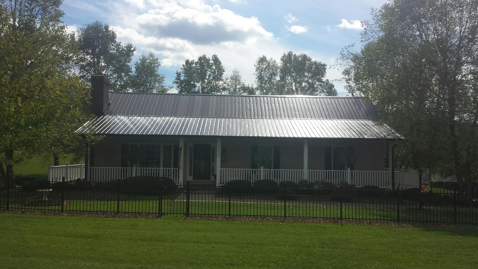 Gray metal roof on a brick ranch with a full width front porch — Gutter Guard Installation work by our crew in Ostrander