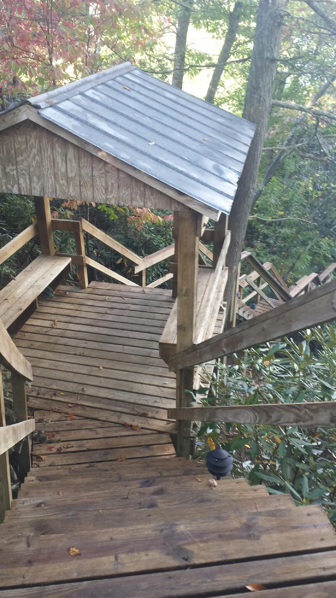 Metal roofed shelter over wooden steps on a wooded walkway — Skylight Repair & Installation work by our crew in Ostrander