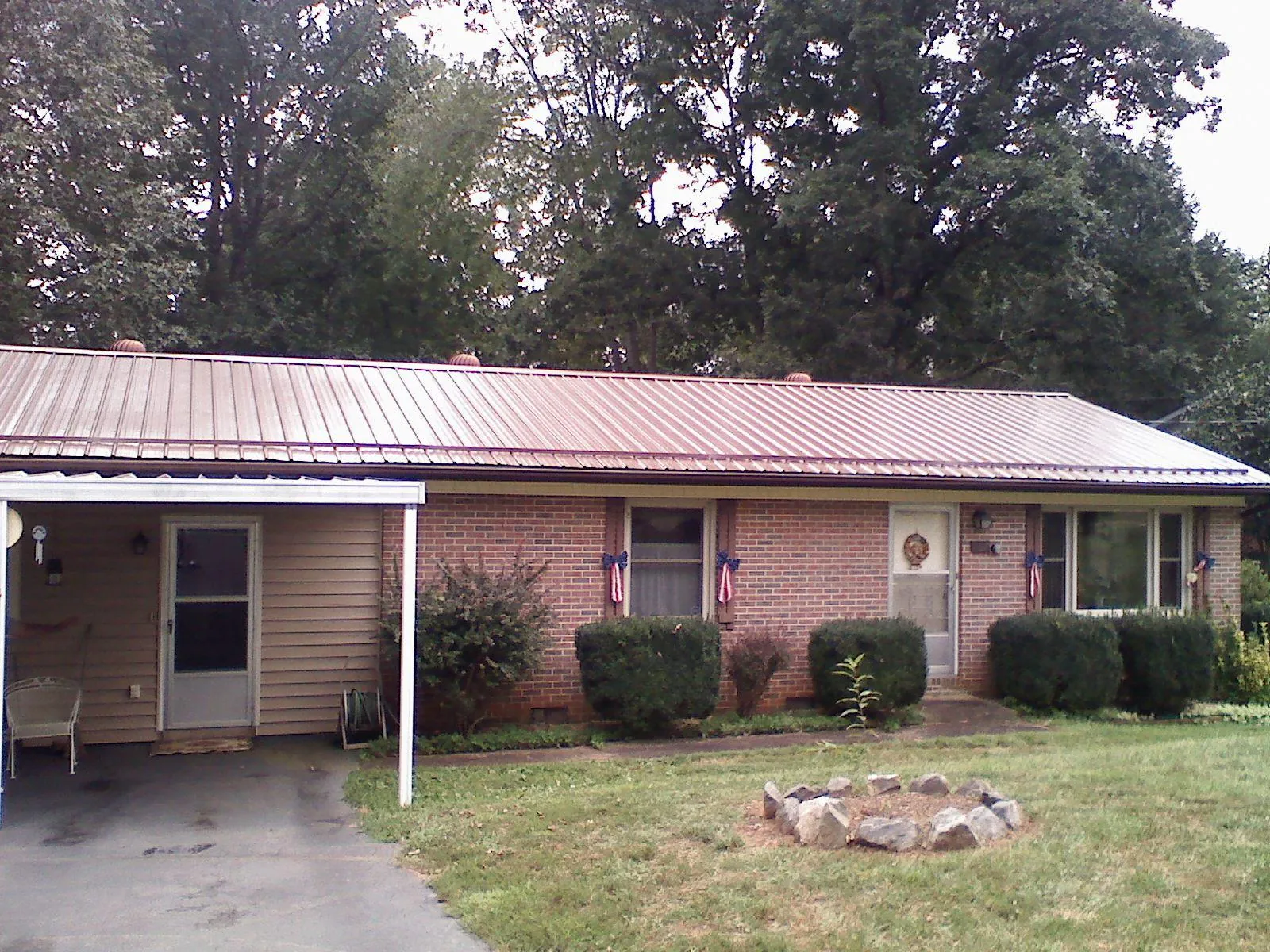 Bronze metal roof and carport on a brick ranch home — Roof Repair work by our crew in Ostrander